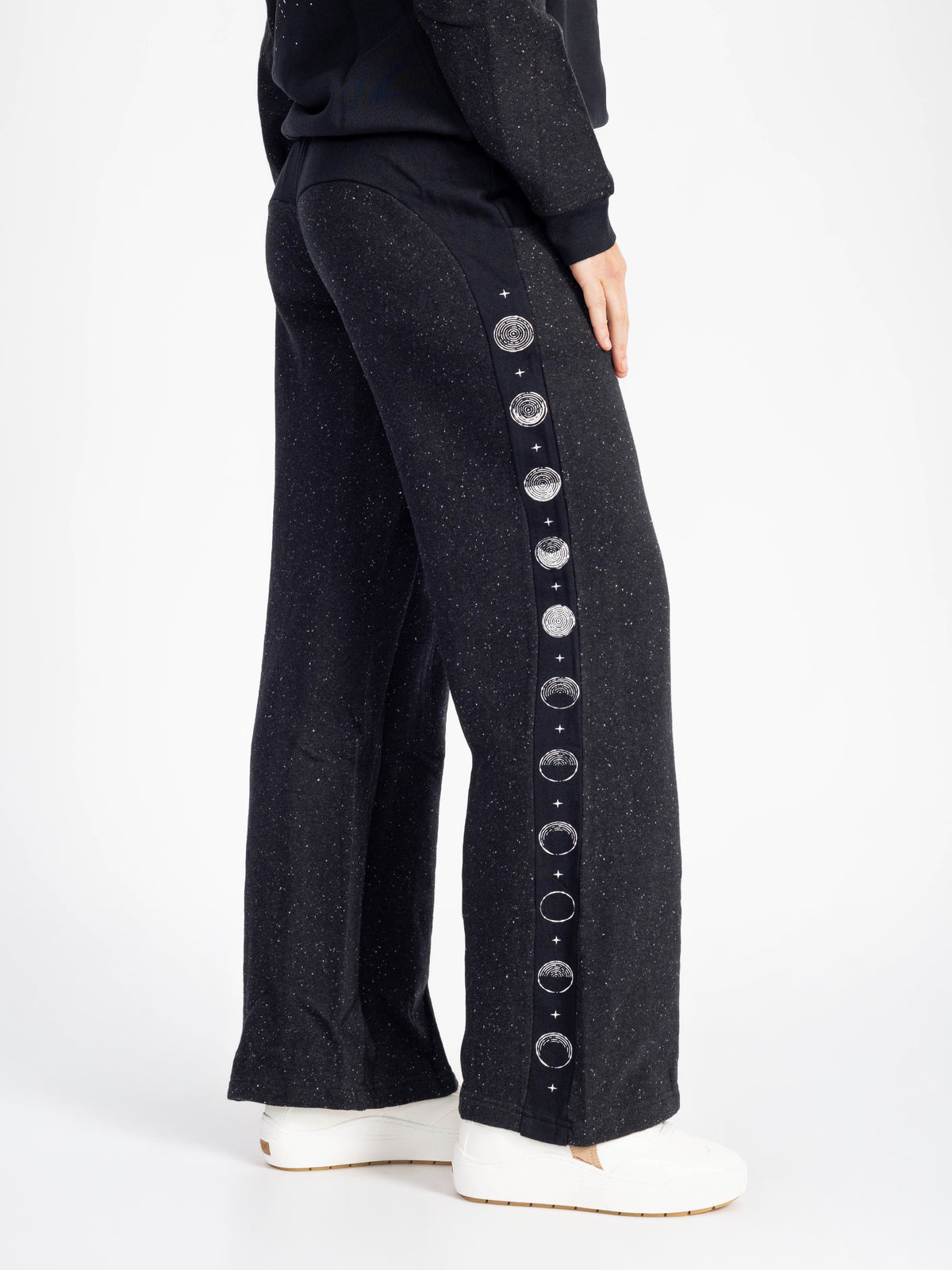 Side view of the speckled black Dark Side organic cotton wide leg sweatpants with moon phase stripe