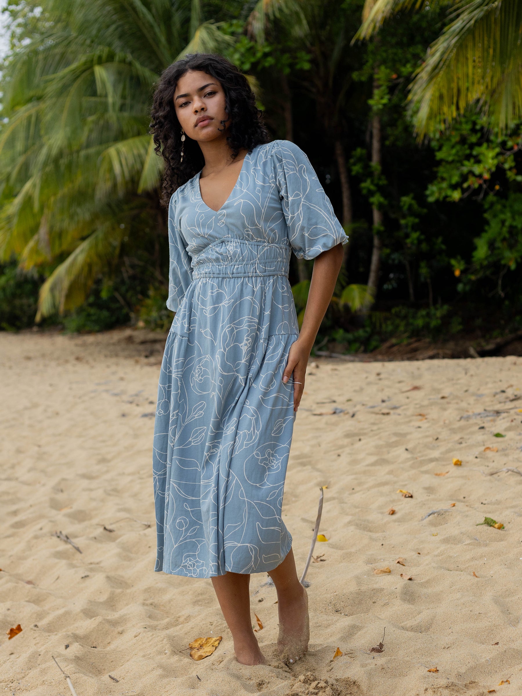 Ophelia Dress in Garden Rose: Blue organic cotton midi dress with white hand-drawn roses, V-neck, puffed sleeves, and smocked waist.