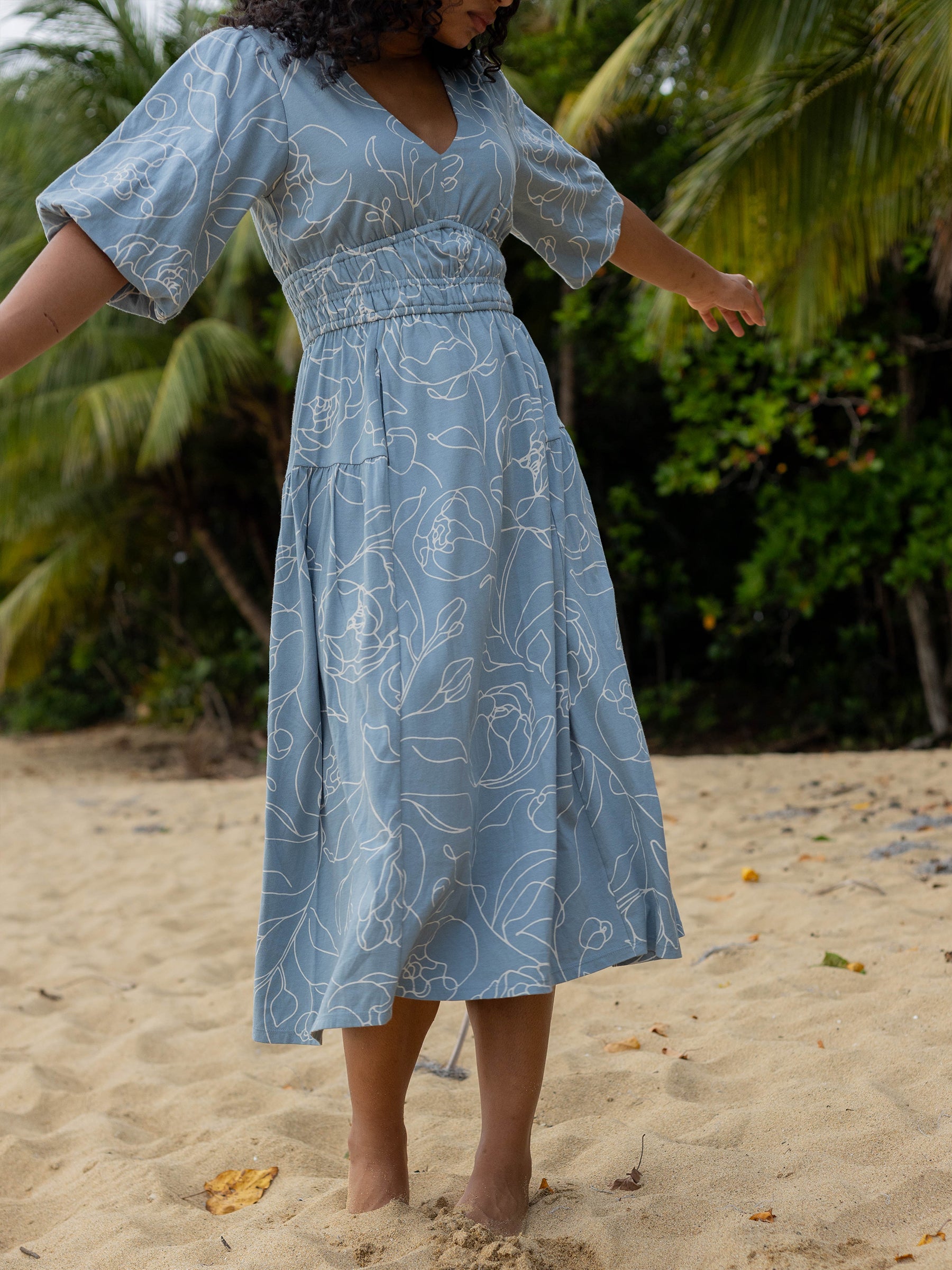Ophelia Dress: Blue organic cotton midi dress with white hand-drawn roses, V-neck, puffed sleeves, and smocked waist.