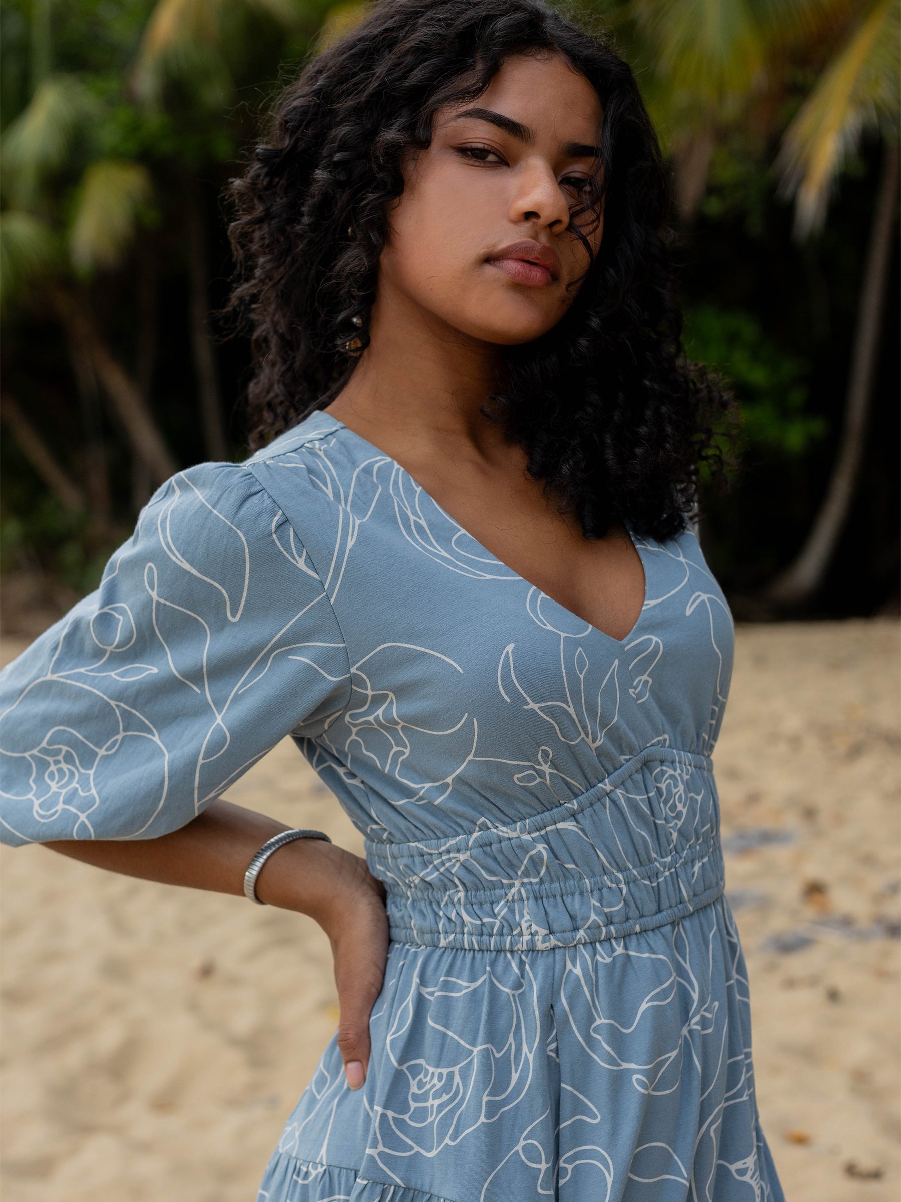 Ophelia Dress in Garden Rose: Blue organic cotton midi dress with white hand-drawn roses, V-neck, puffed sleeves, and smocked waist.