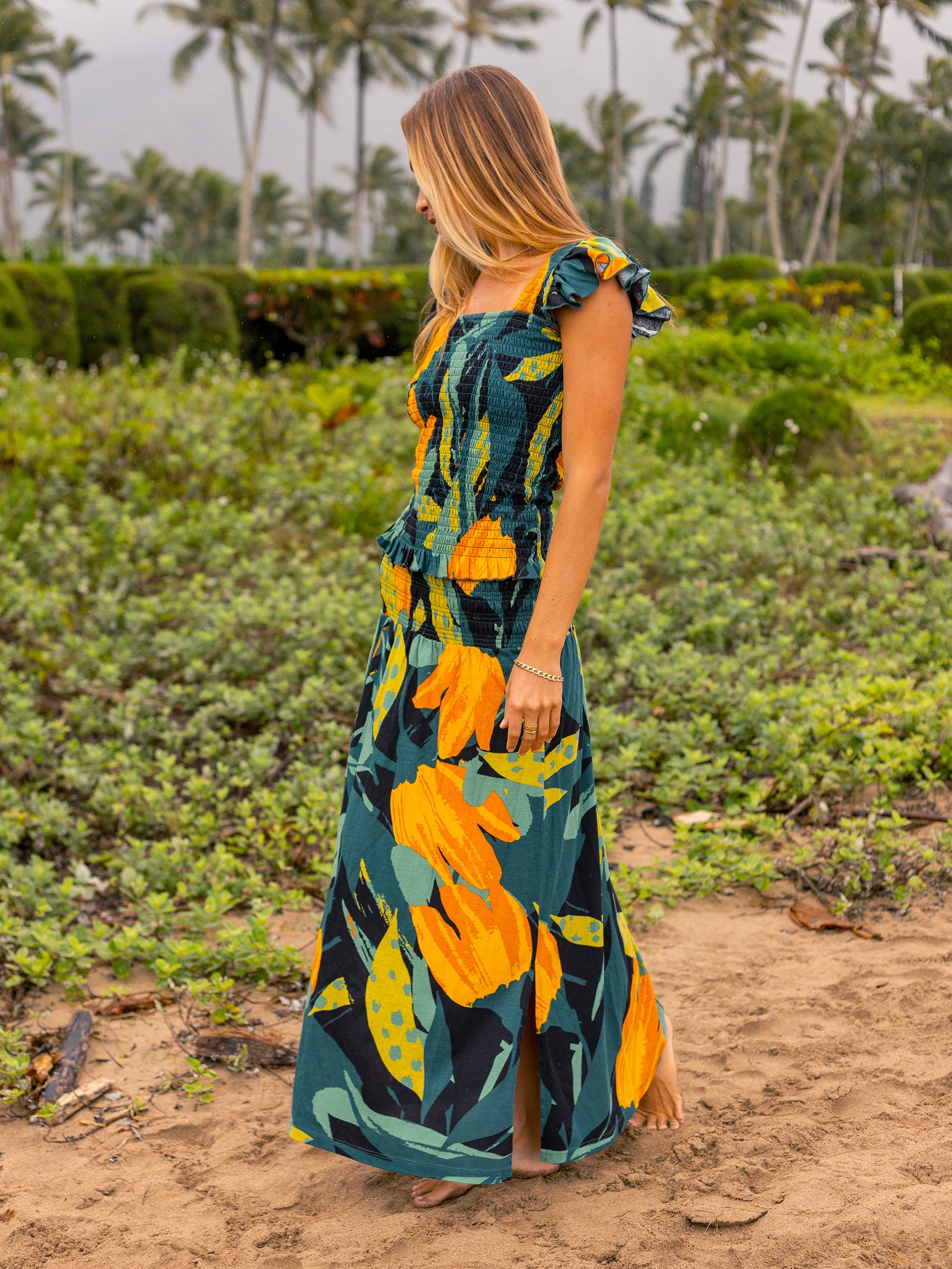 Woman in a Hanalei smocked top and maxi skirt set, featuring a green, yellow, and orange floral print.
