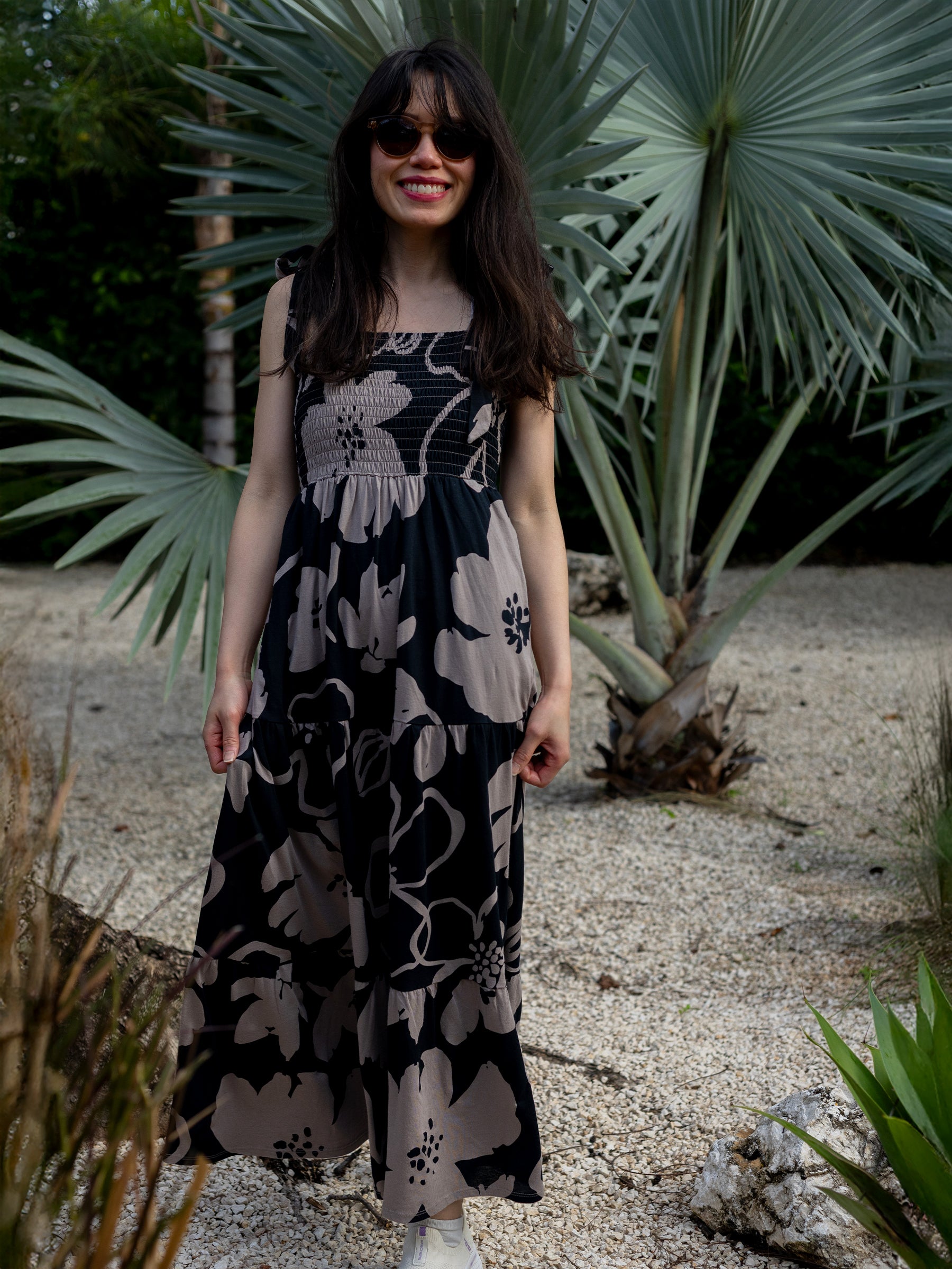 Woman in Evie Moonflower smocked maxi dress with large taupe florals, ribbon ties, and tiered skirt.