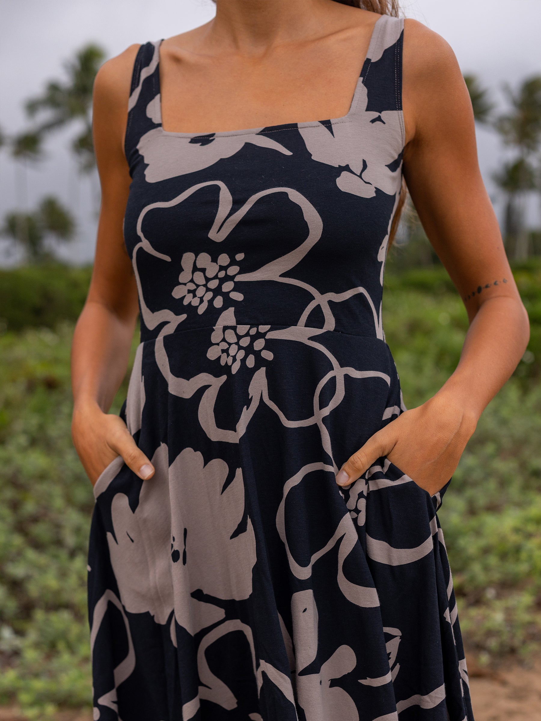 Lily Dress in Moonflower: black organic cotton midi dress with taupe floral print, square neckline, wide straps, and pockets.