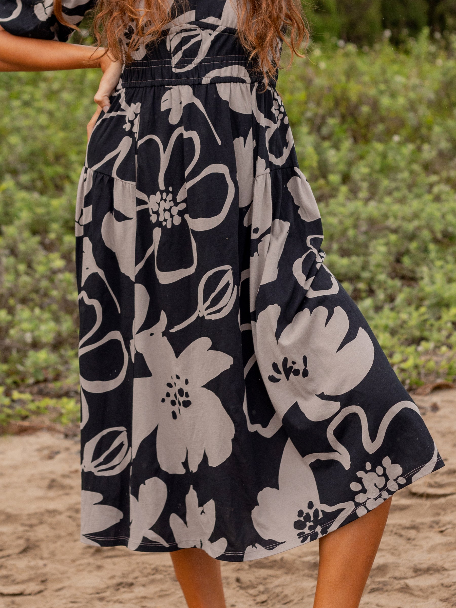 Ophelia Moonflower midi dress: black organic cotton with large taupe floral print, smocked waist, and flowy skirt.