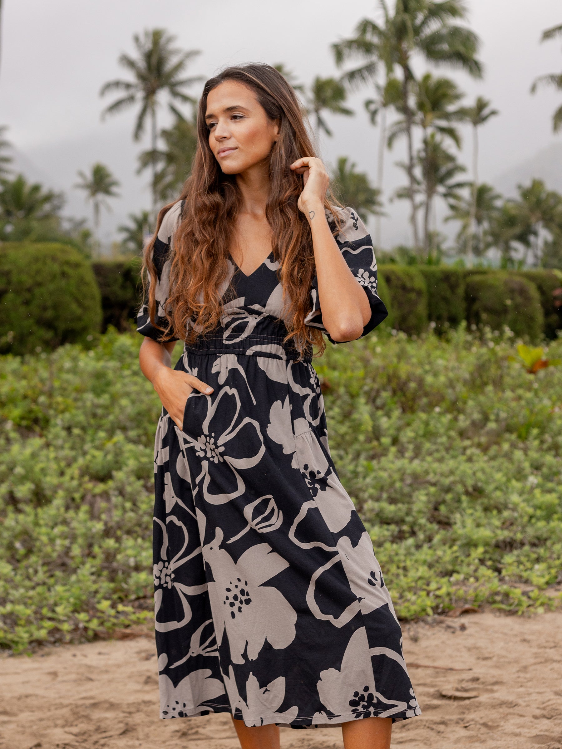 Woman in a black and taupe floral Ophelia midi dress with V-neck, puffed sleeves, smocked waist, and pockets.