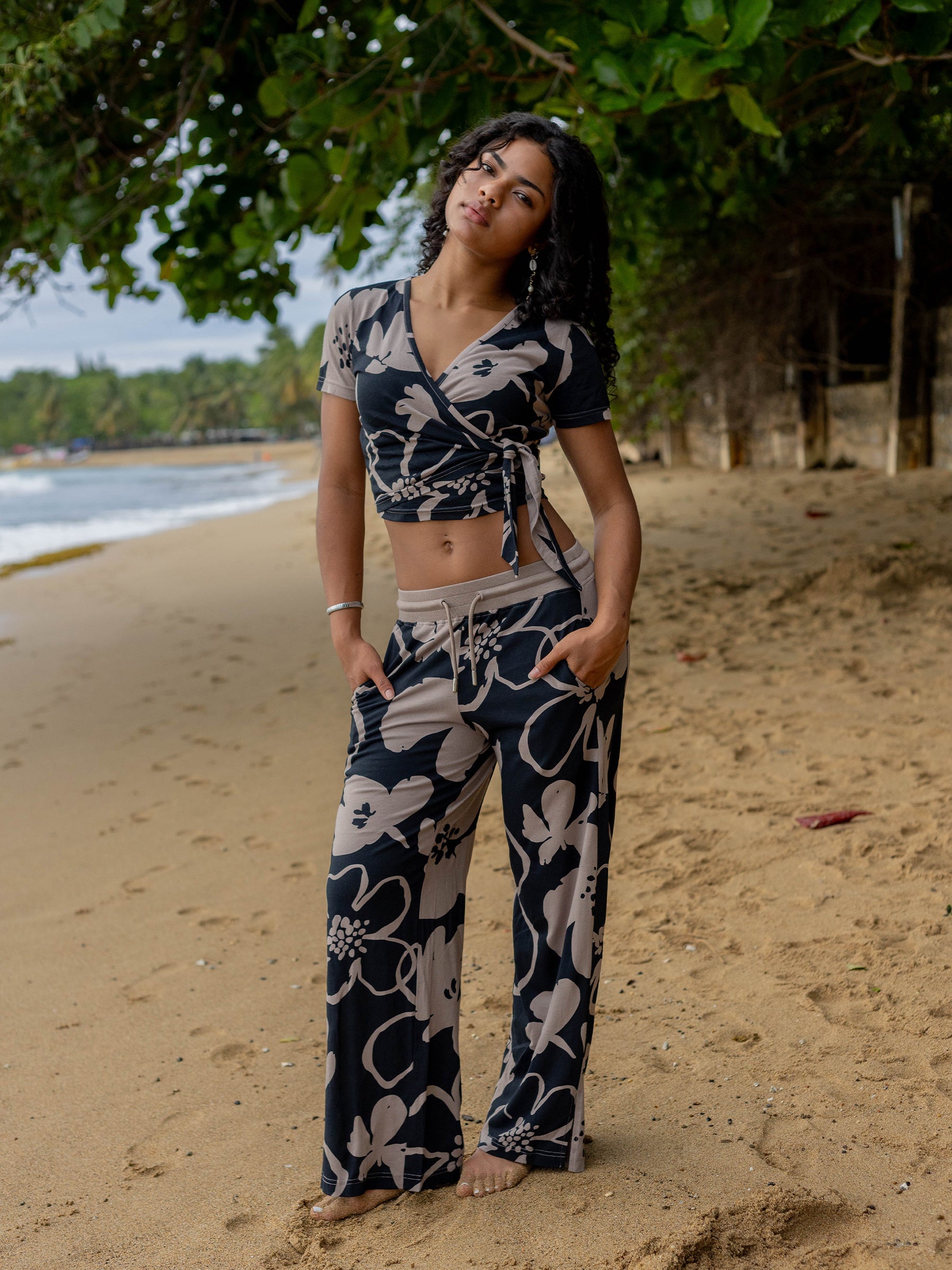 Woman on beach wearing a Moonflower wrap crop top and matching pants with taupe floral print.