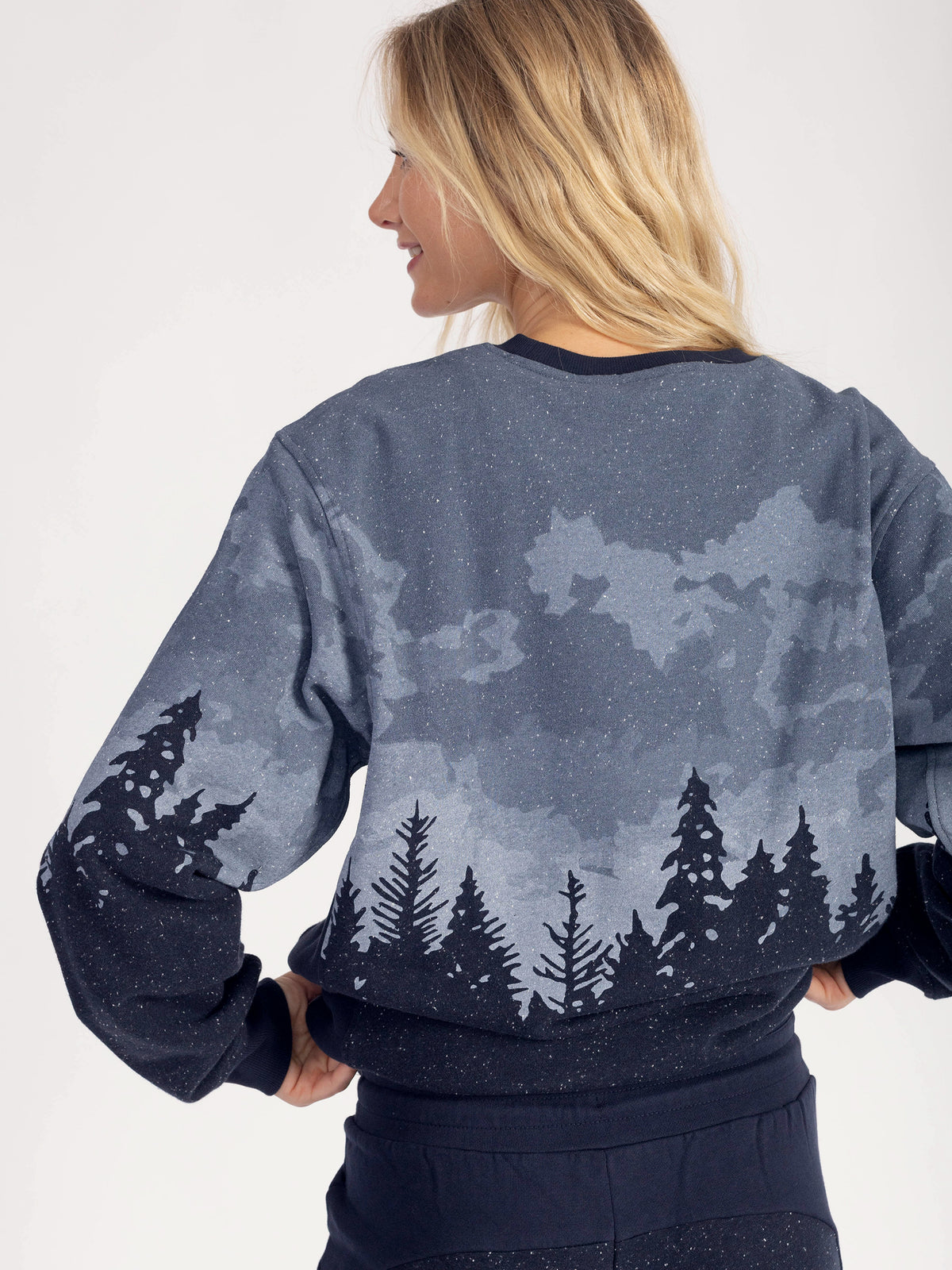 Back view of the Stardust organic cotton sweatshirt, pine forest silhouette across the back