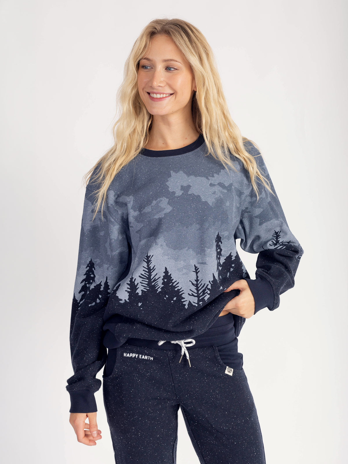 Smiling model wearing the Stardust organic cotton sweatshirt, hand in sweatpants pocket