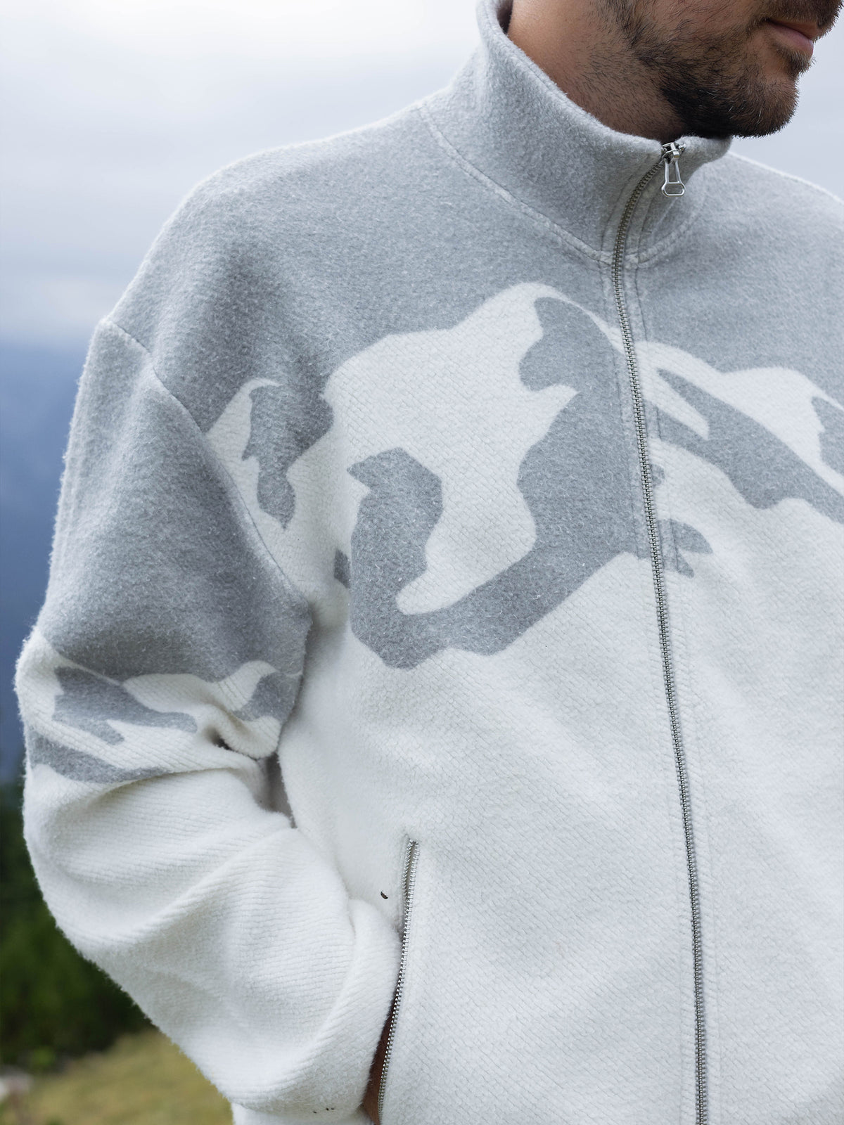 Close-up of the stand collar and gray mountain design on the white Altitude organic cotton sherpa jacket