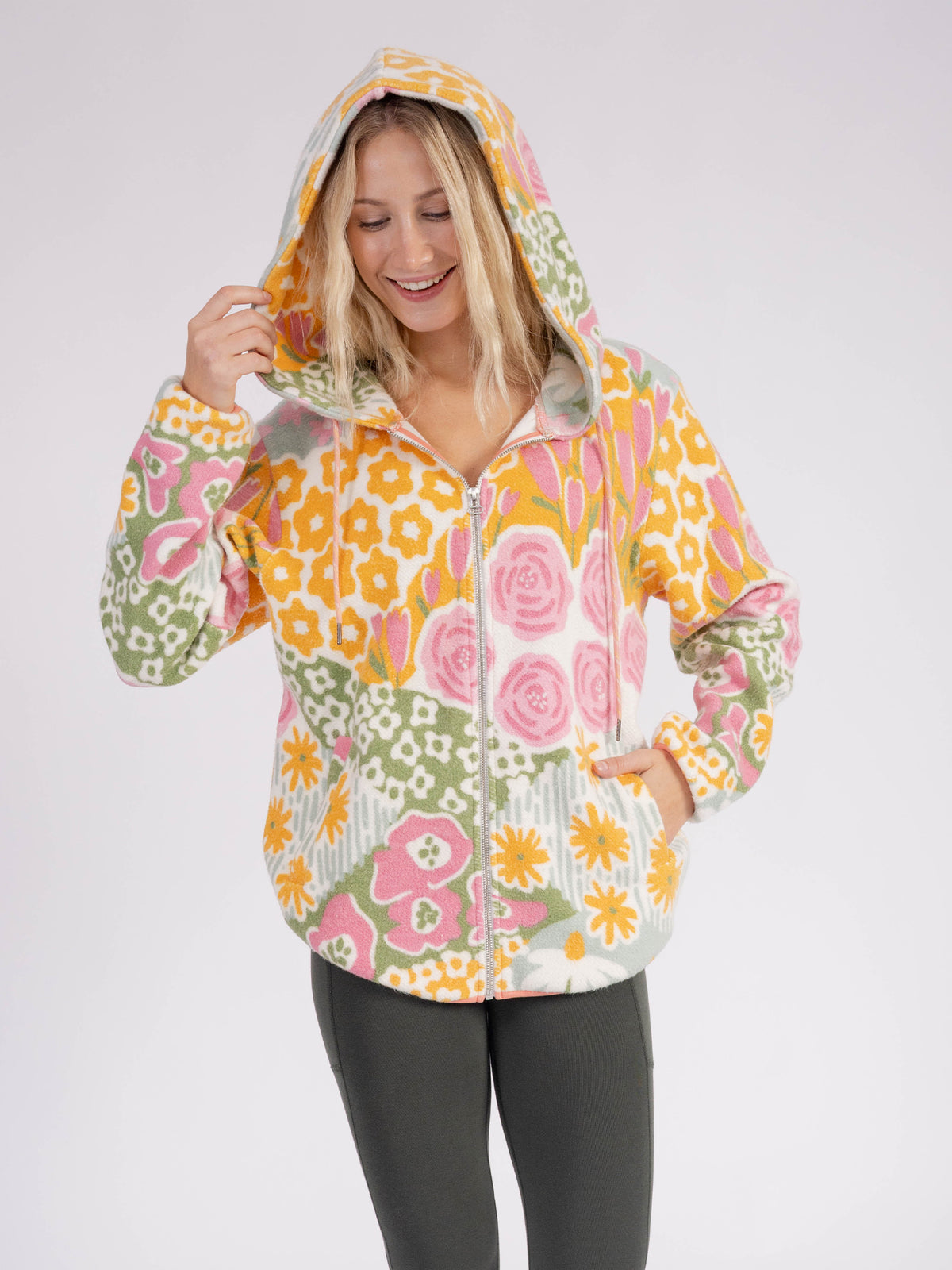 Smiling model wearing the floral Bouquet organic cotton sherpa zip hoodie with the hood up
