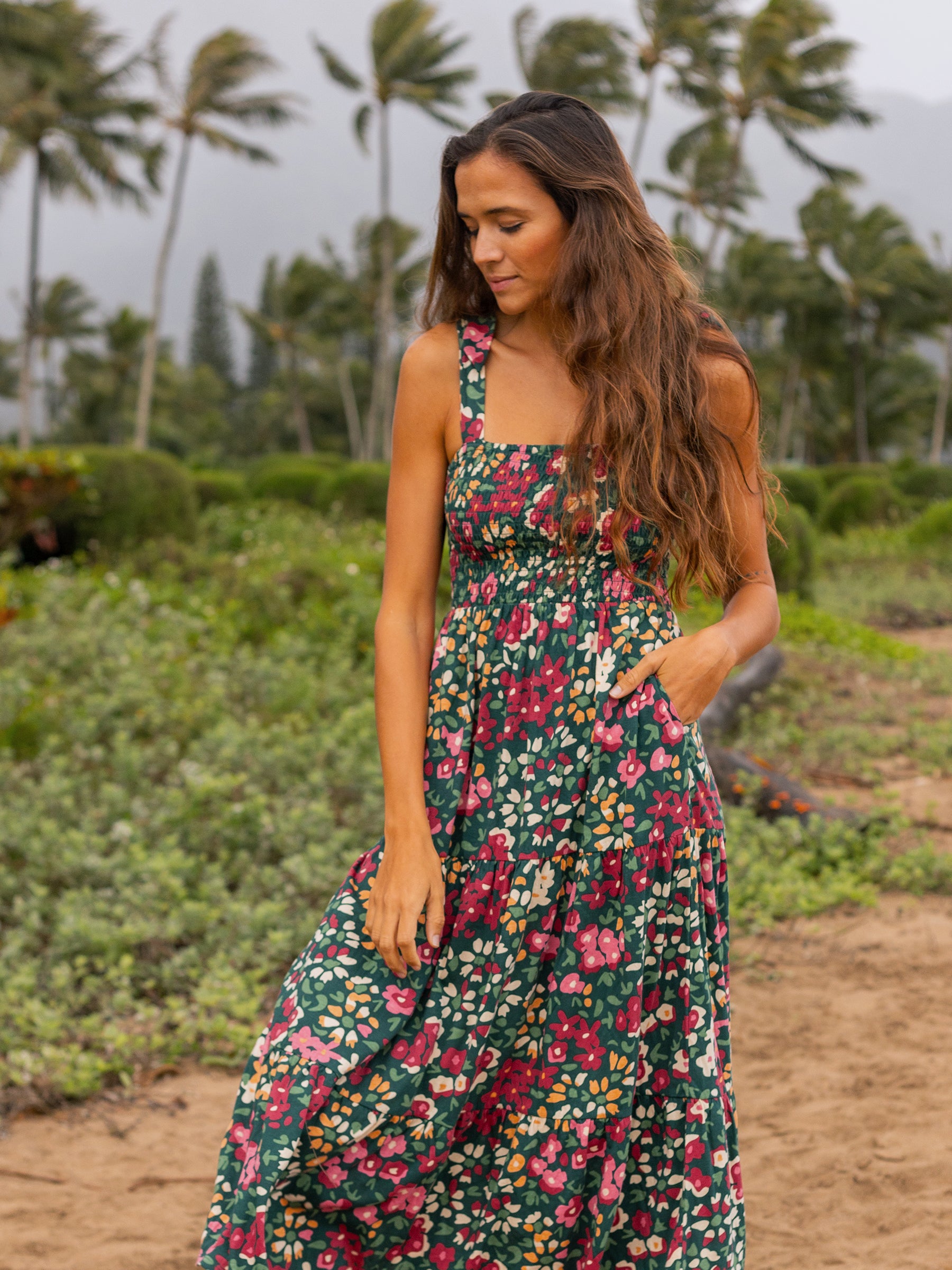 Woman in a green Evie Smocked Dress with red and pink wildflowers, smocked bodice, and tiered maxi skirt.