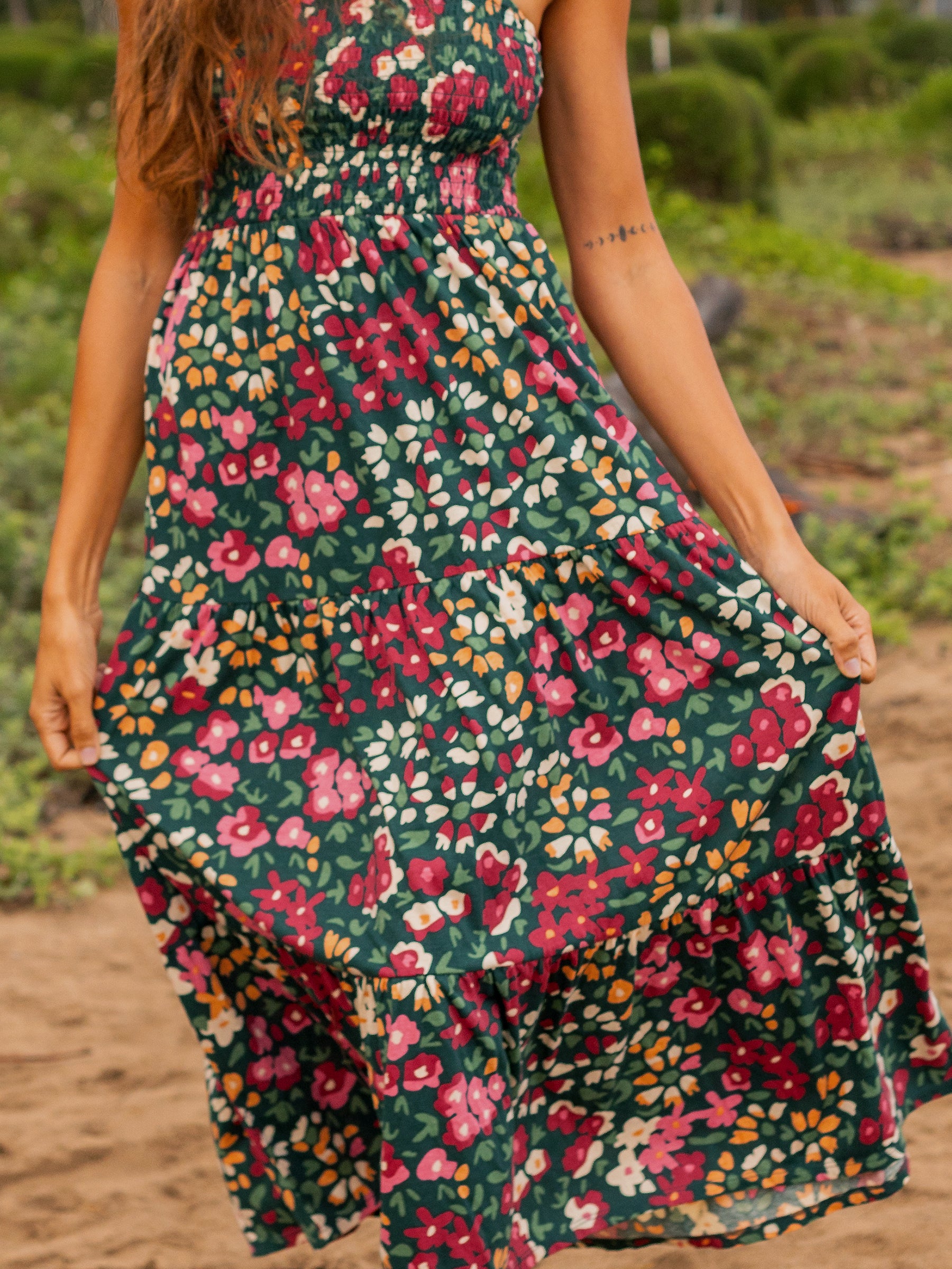 Evie Smocked Dress in Wildflowers print: dark green organic cotton maxi with smocked bodice and tiered skirt.