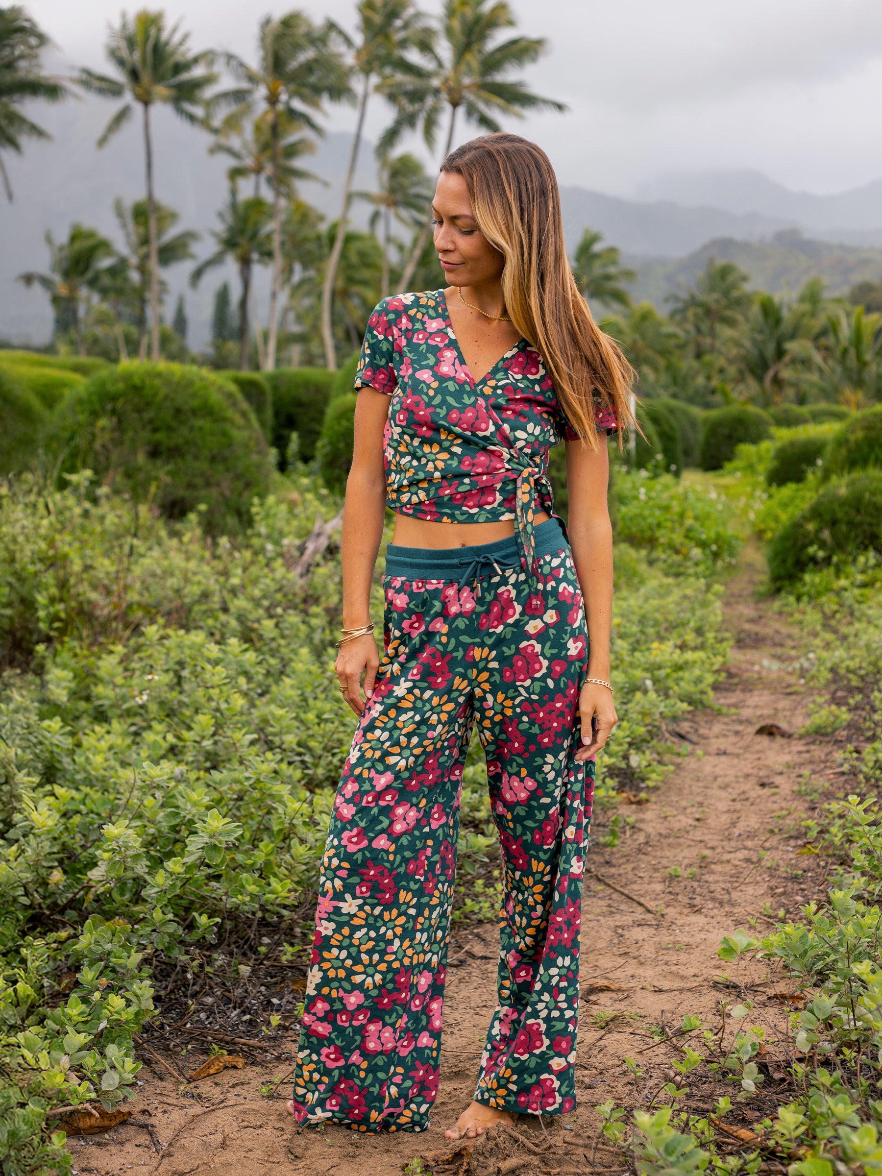 Woman in a dark green organic cotton wide-leg pants and matching wrap top with a vibrant wildflower print.