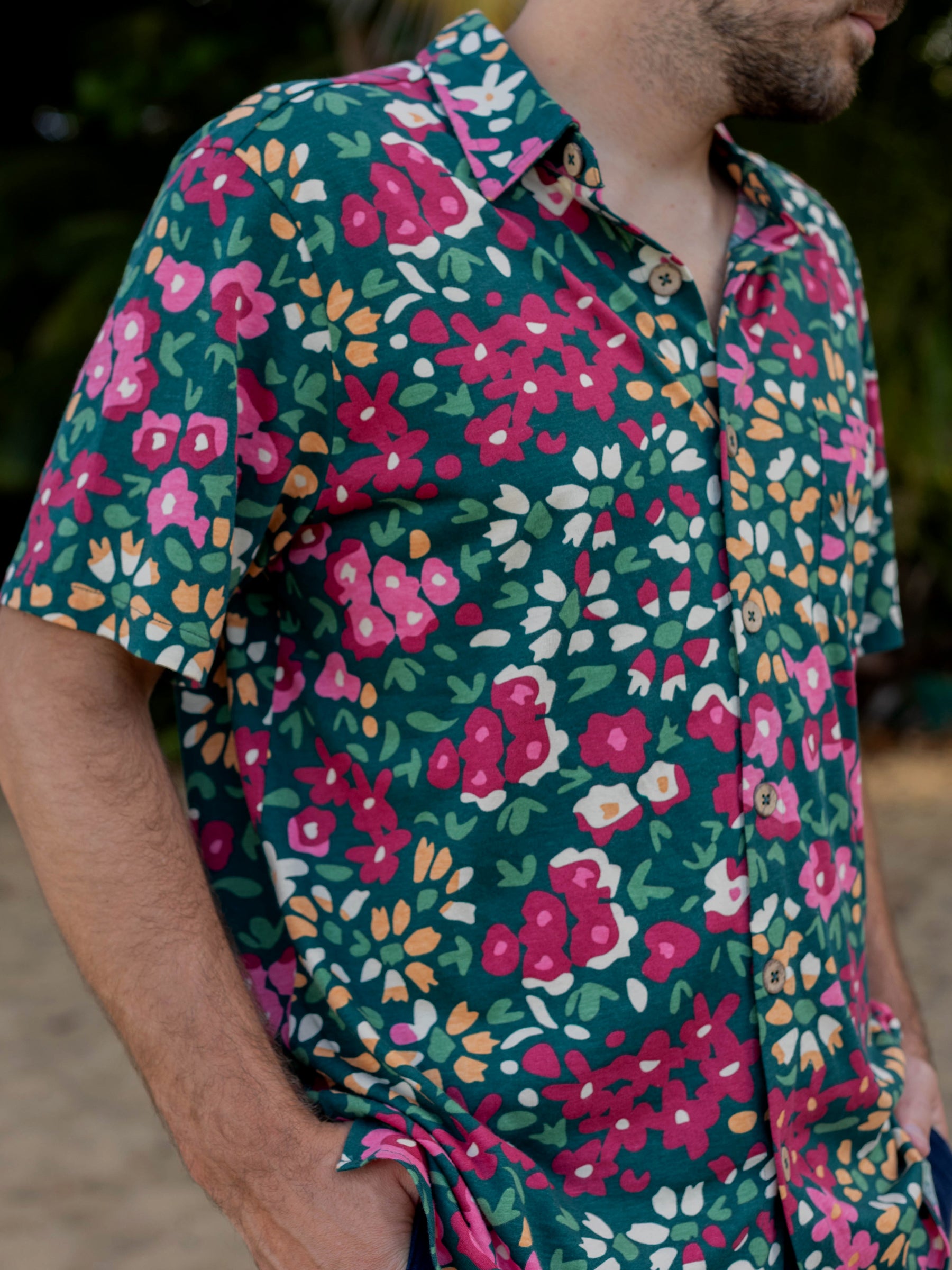 Men's Rincon Shirt in dark green organic cotton jersey with vibrant pink, red, and yellow wildflower print.