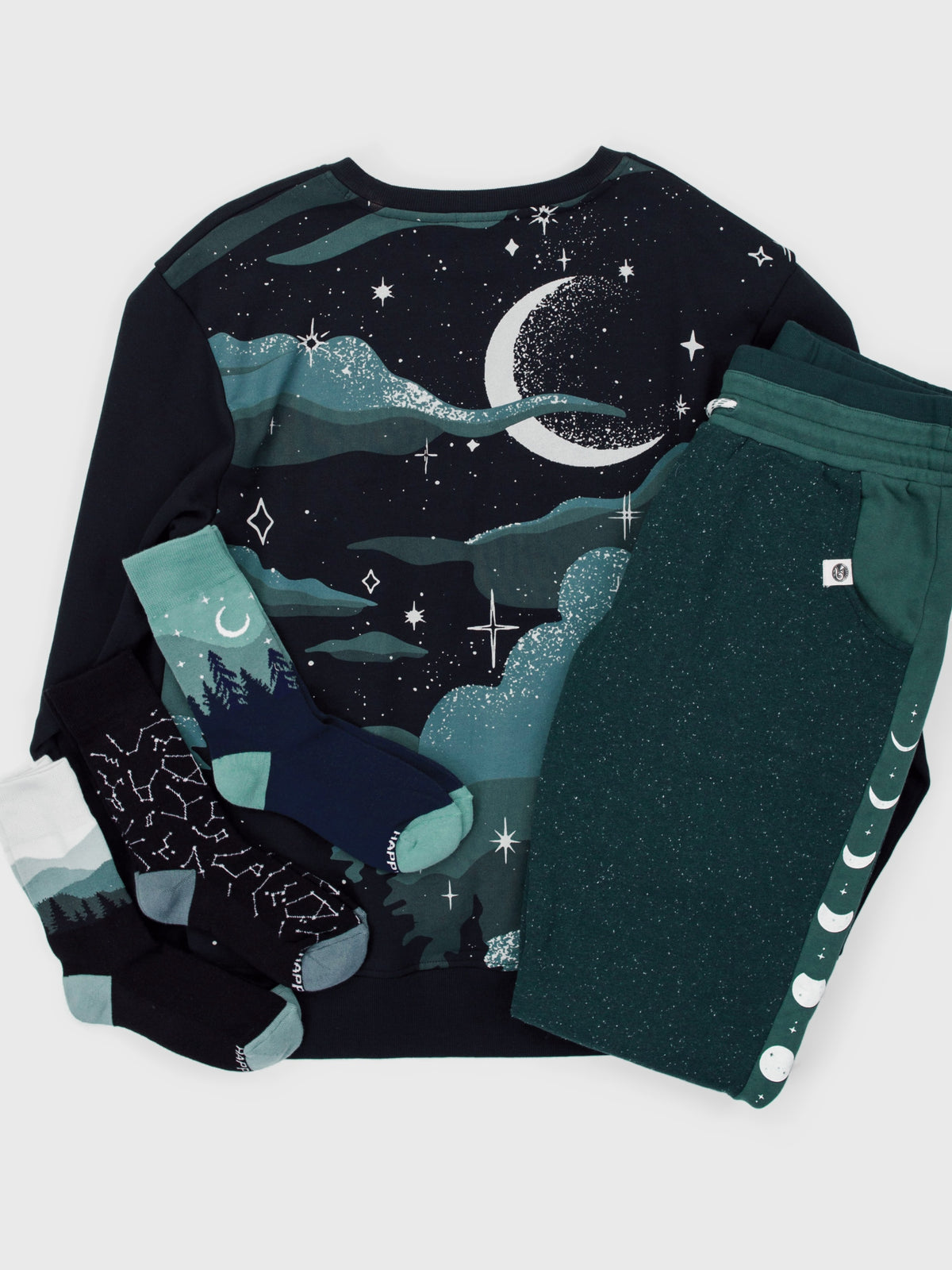 Nocturne Pullover Bundle flat lay: Nocturne organic cotton pullover, Lunar Glow joggers, and Constellations, Aurora and Smoky Mountains socks
