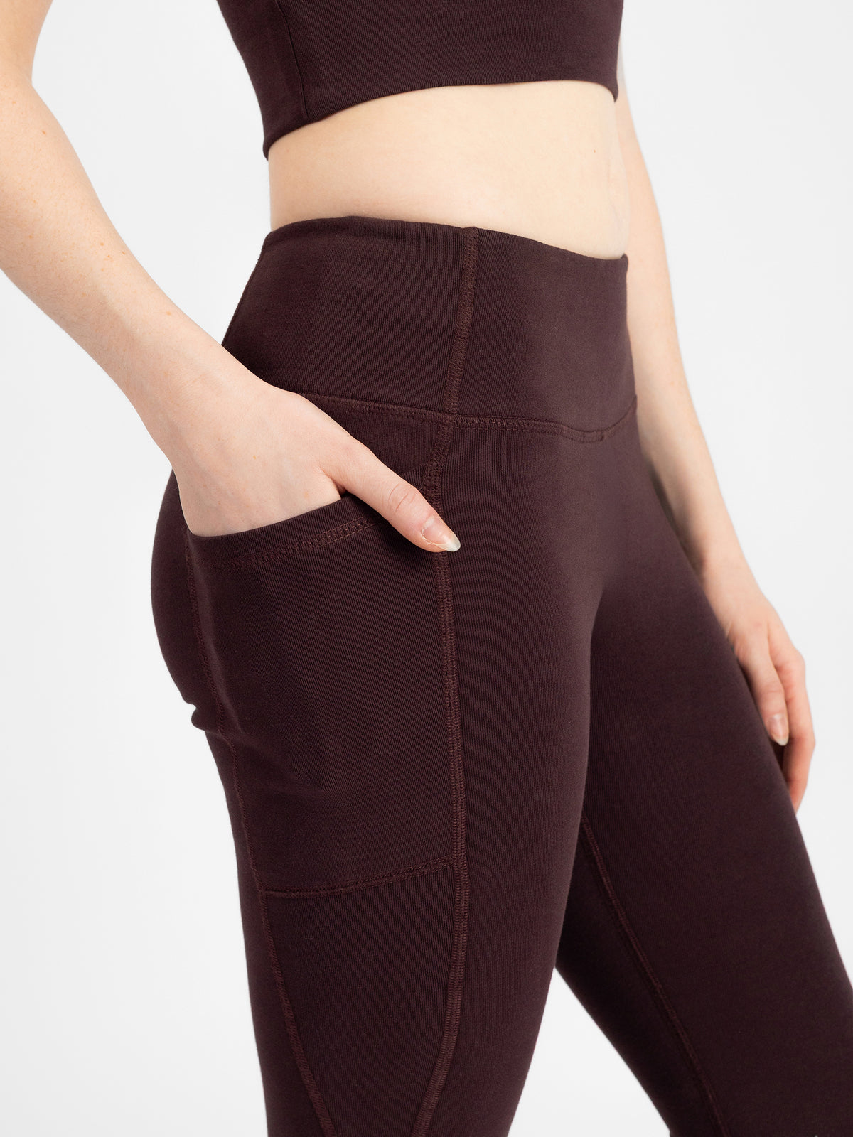 Close-up of the Espresso brown PlantTec organic cotton flare leggings with hand in the side pocket