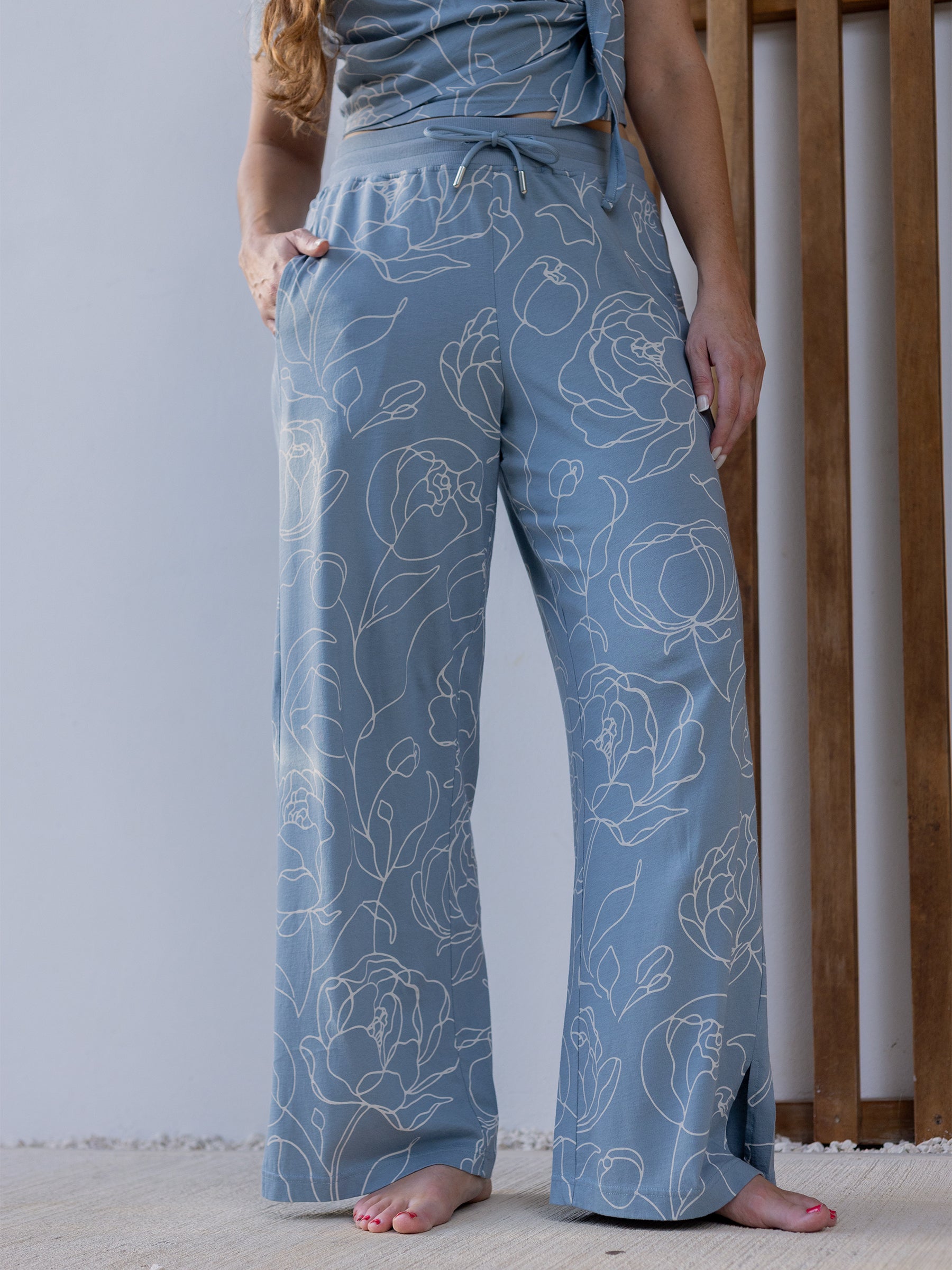 Wide-leg organic cotton pants in garden rose print, light blue with white floral design, side slit, and drawstring waist.