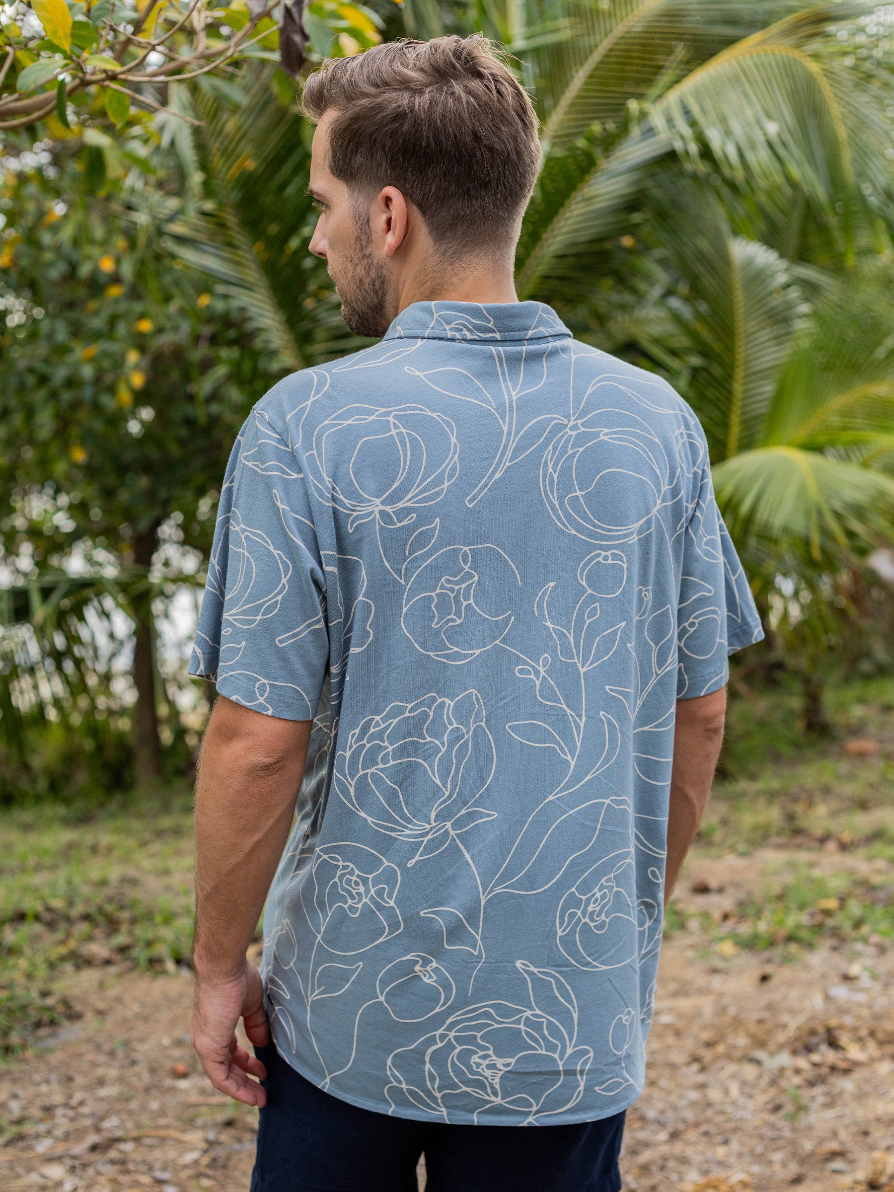 Men's Rincon Shirt in Garden Rose, a blue organic cotton jersey with white hand-drawn rose print.