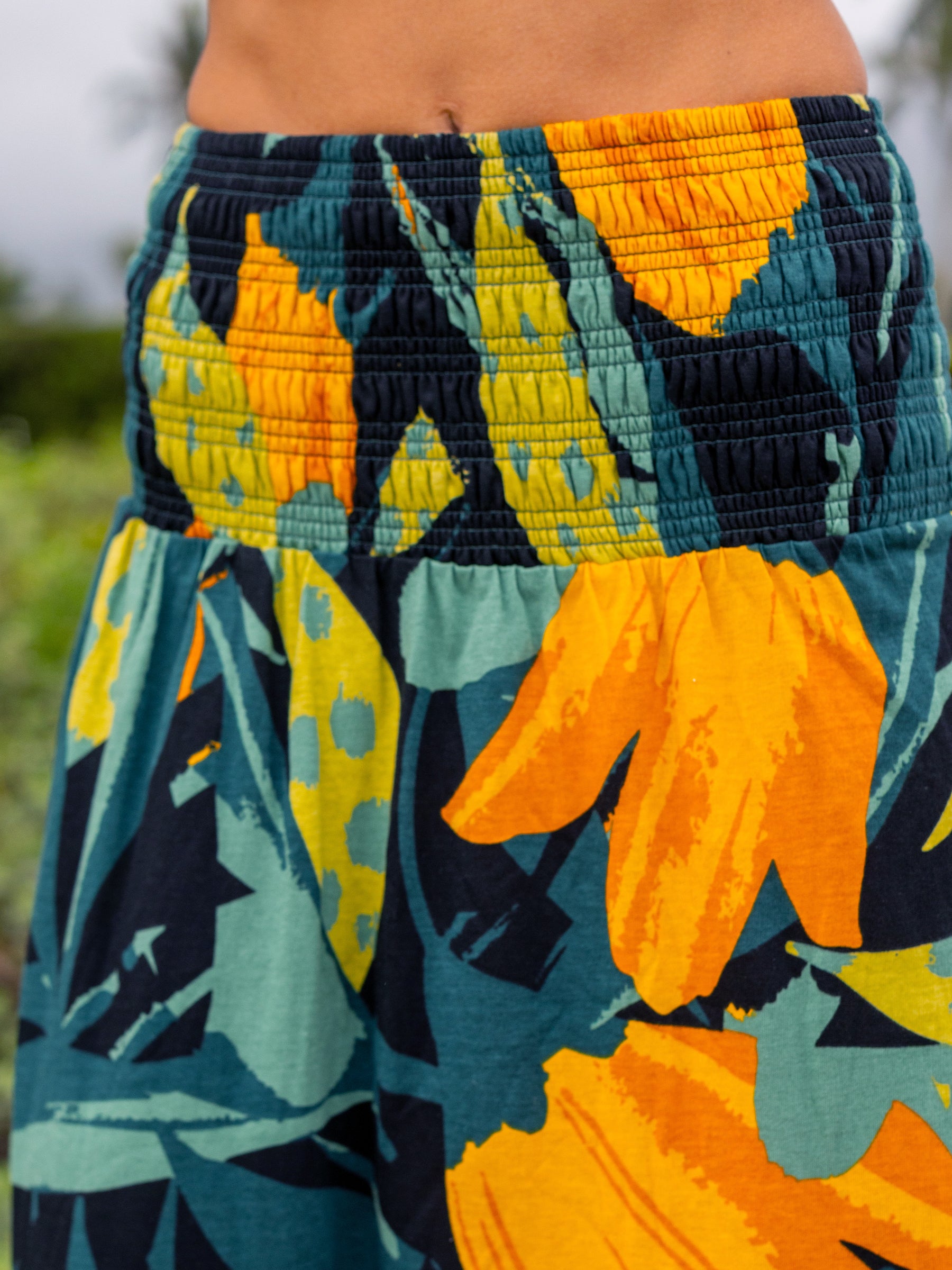 Hanalei Smocked Skirt in organic cotton with a wide smocked waistband and vibrant green and golden floral print.