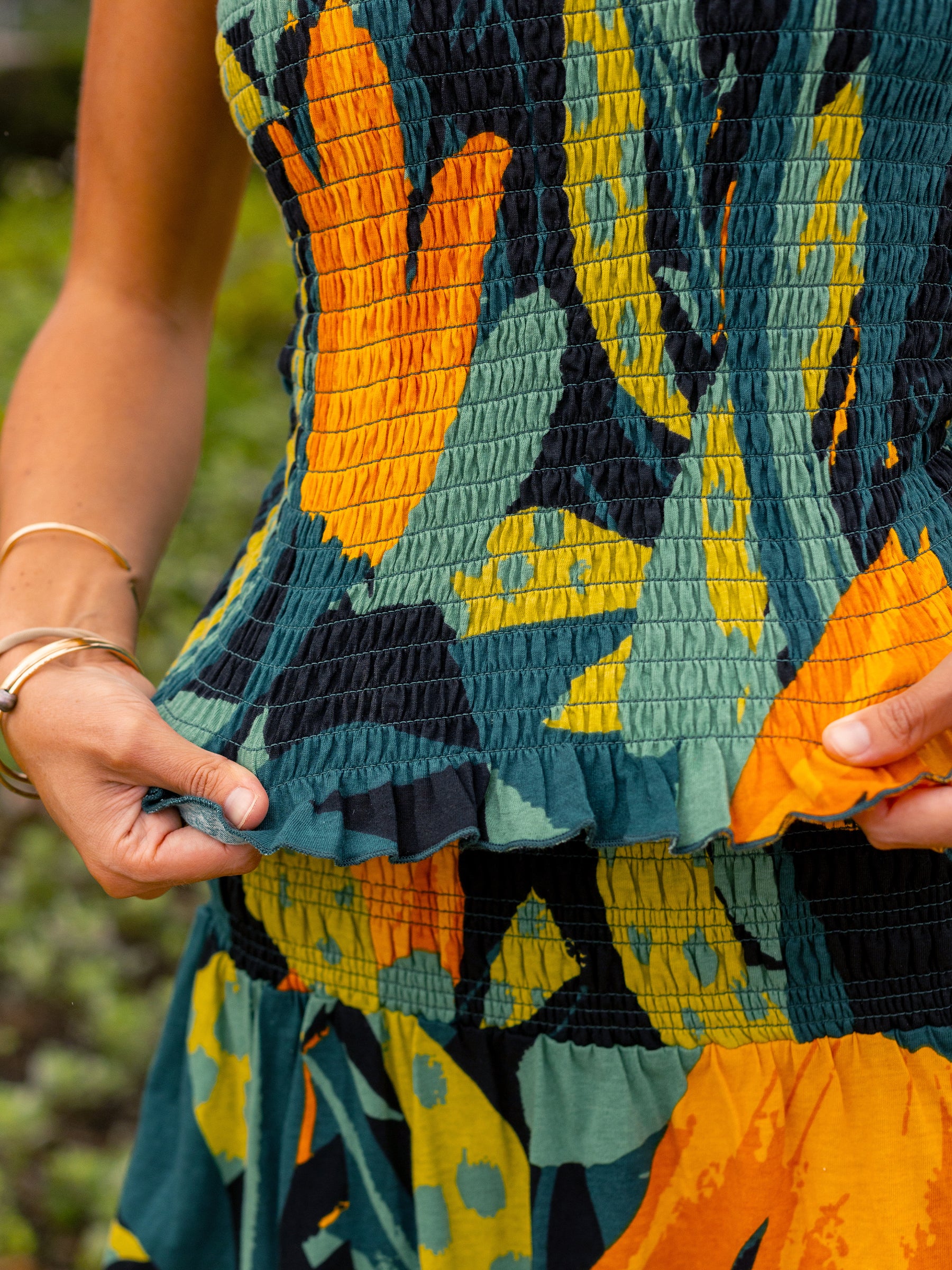 Smocked Hanalei top in organic cotton with a vibrant green, yellow, and black tropical print.