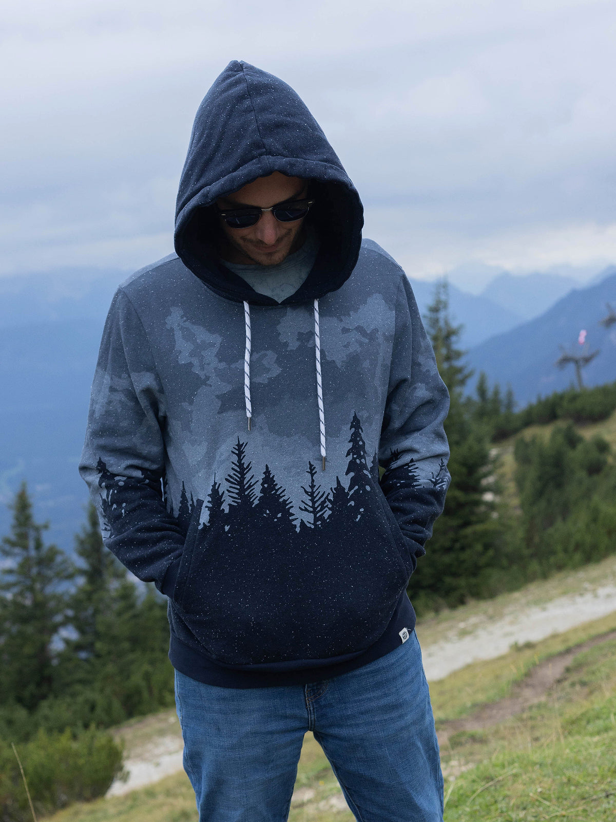 Model in sunglasses wearing the Stardust organic cotton hoodie, hood up, hands in pockets