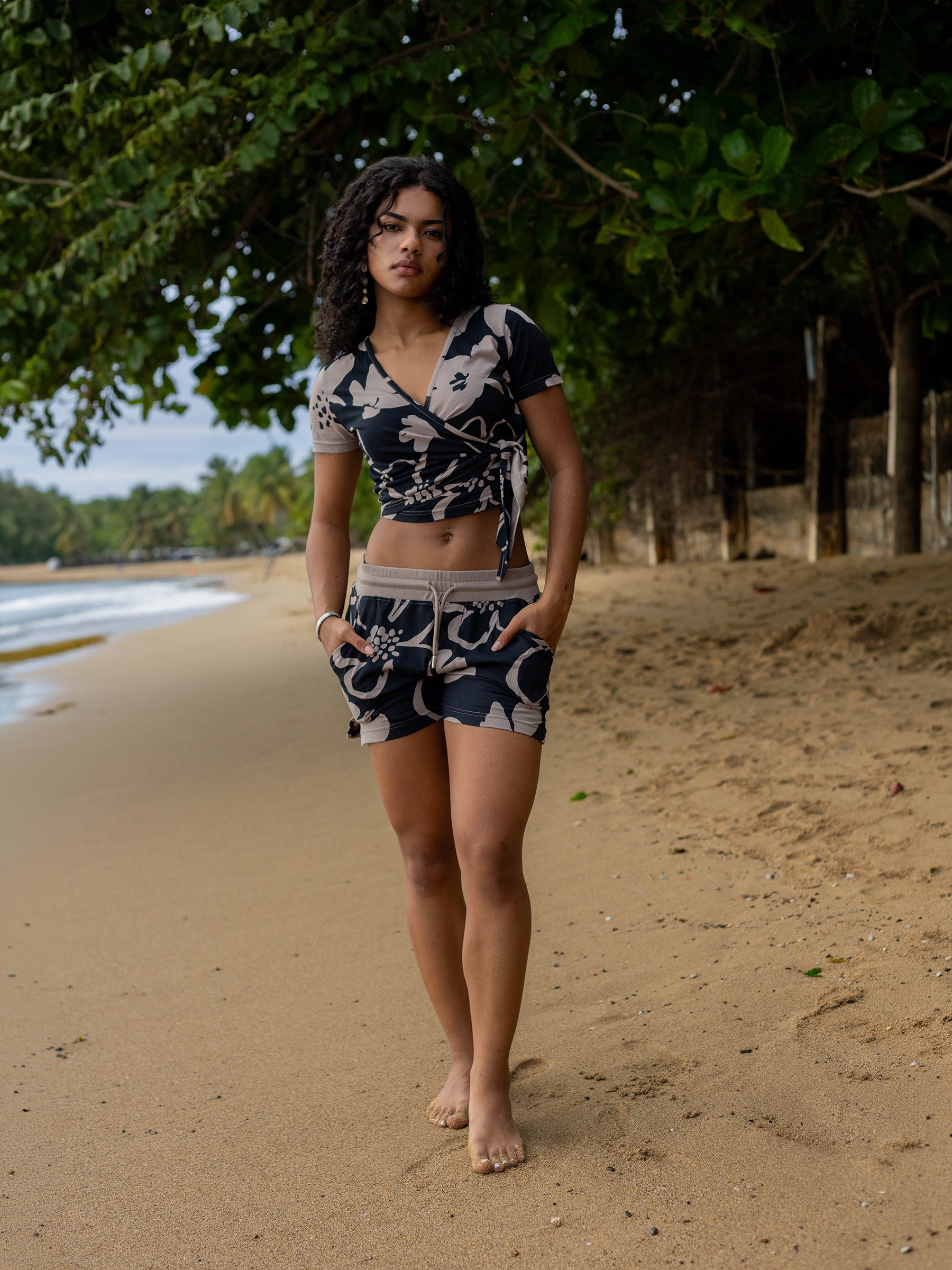 Woman on beach wearing a Moonflower Wrap Crop Top and matching shorts with taupe floral print.