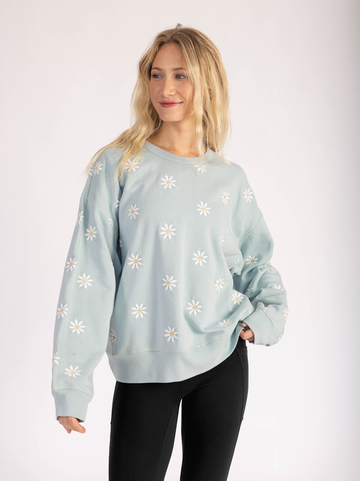 Model wearing the Daisies organic cotton sweatshirt in light blue with black leggings