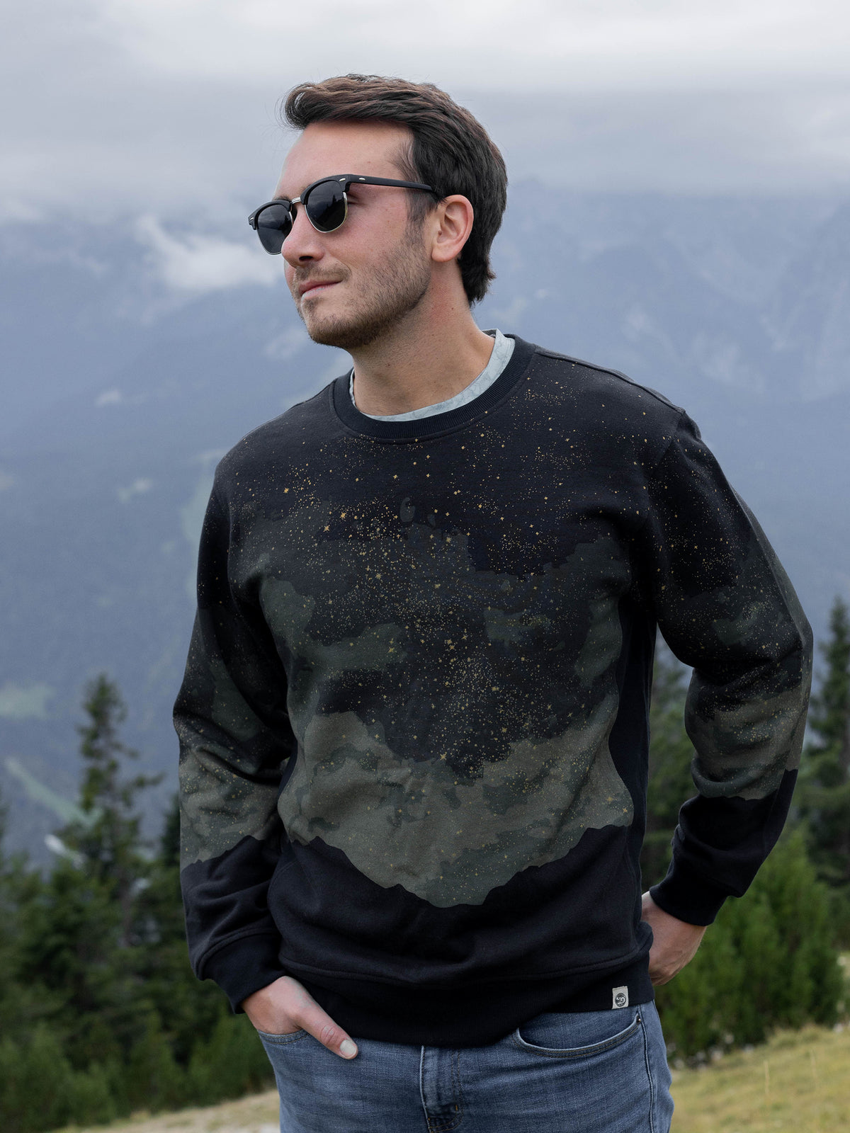 Model wearing the black Embercrest organic cotton sweatshirt with a starry night mountain design, front view