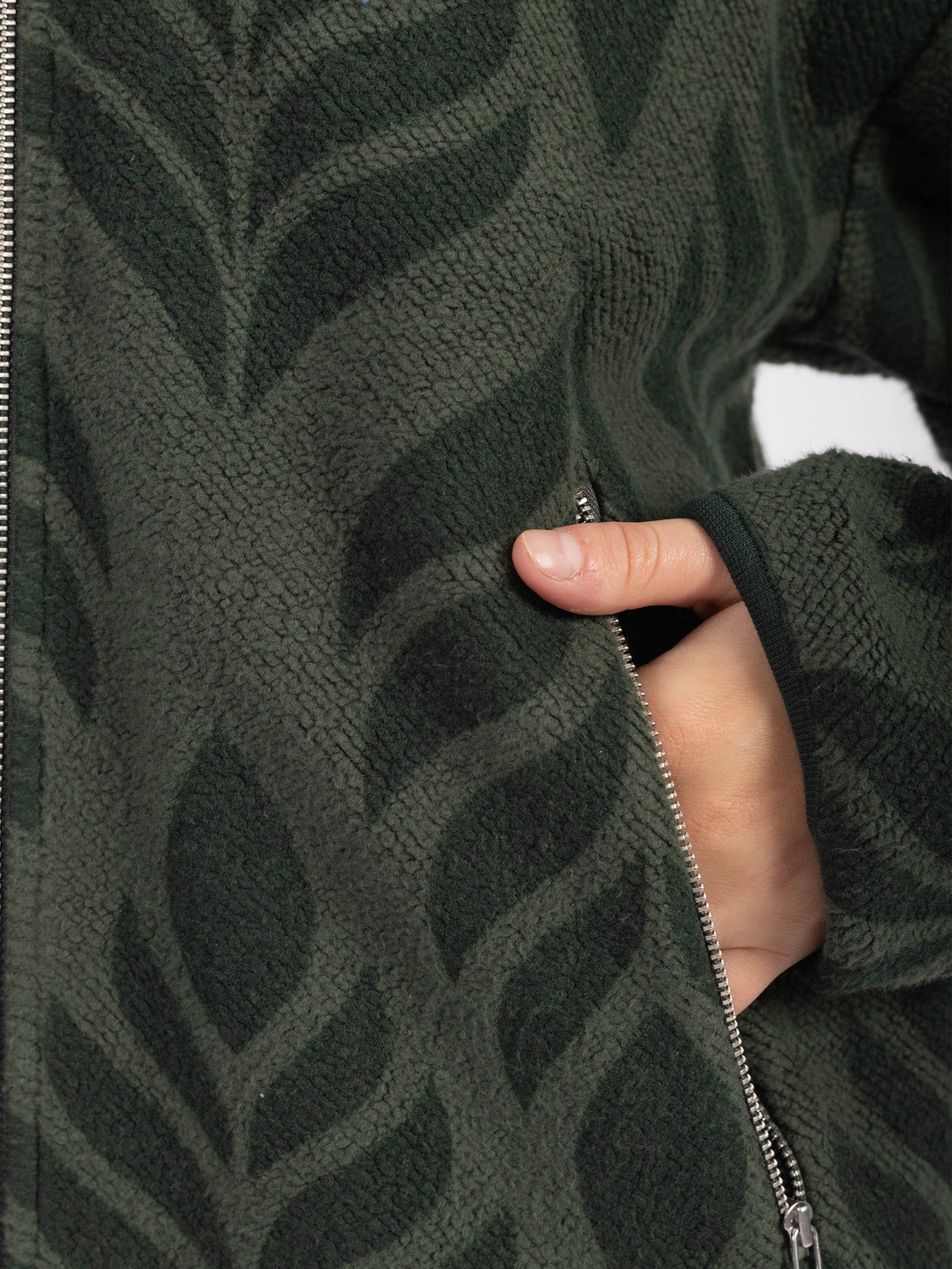 Close-up of a zippered pocket and leaf pattern on the Verdant organic cotton sherpa jacket