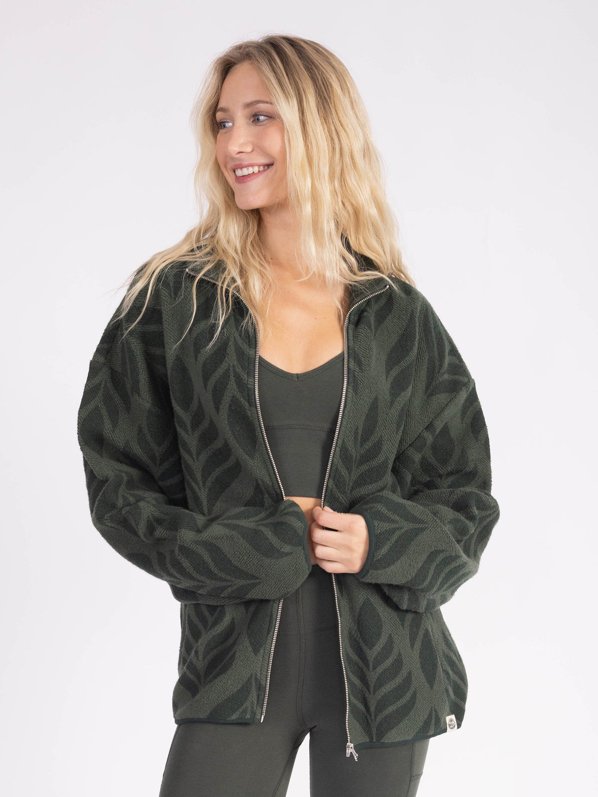 Model wearing the Verdant organic cotton sherpa jacket unzipped, leaf pattern sherpa