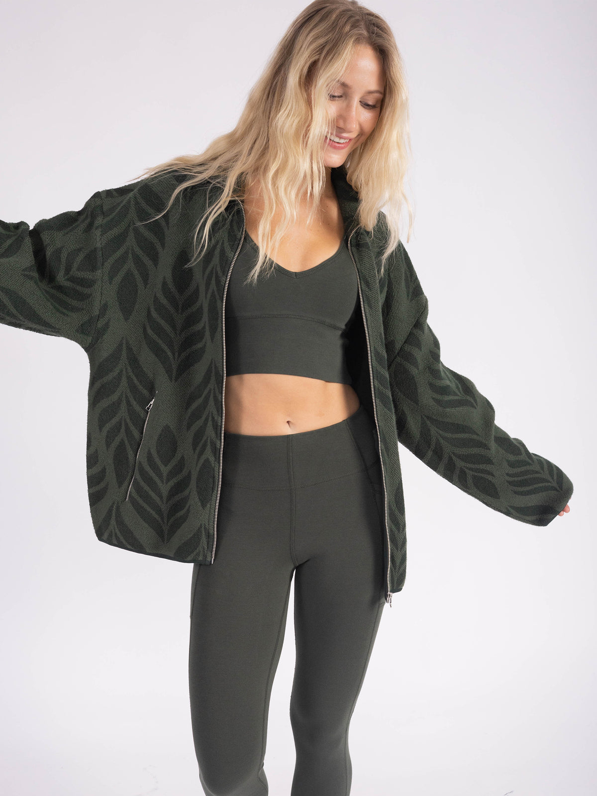 Model wearing the Verdant organic cotton sherpa jacket open over a sports bra and leggings