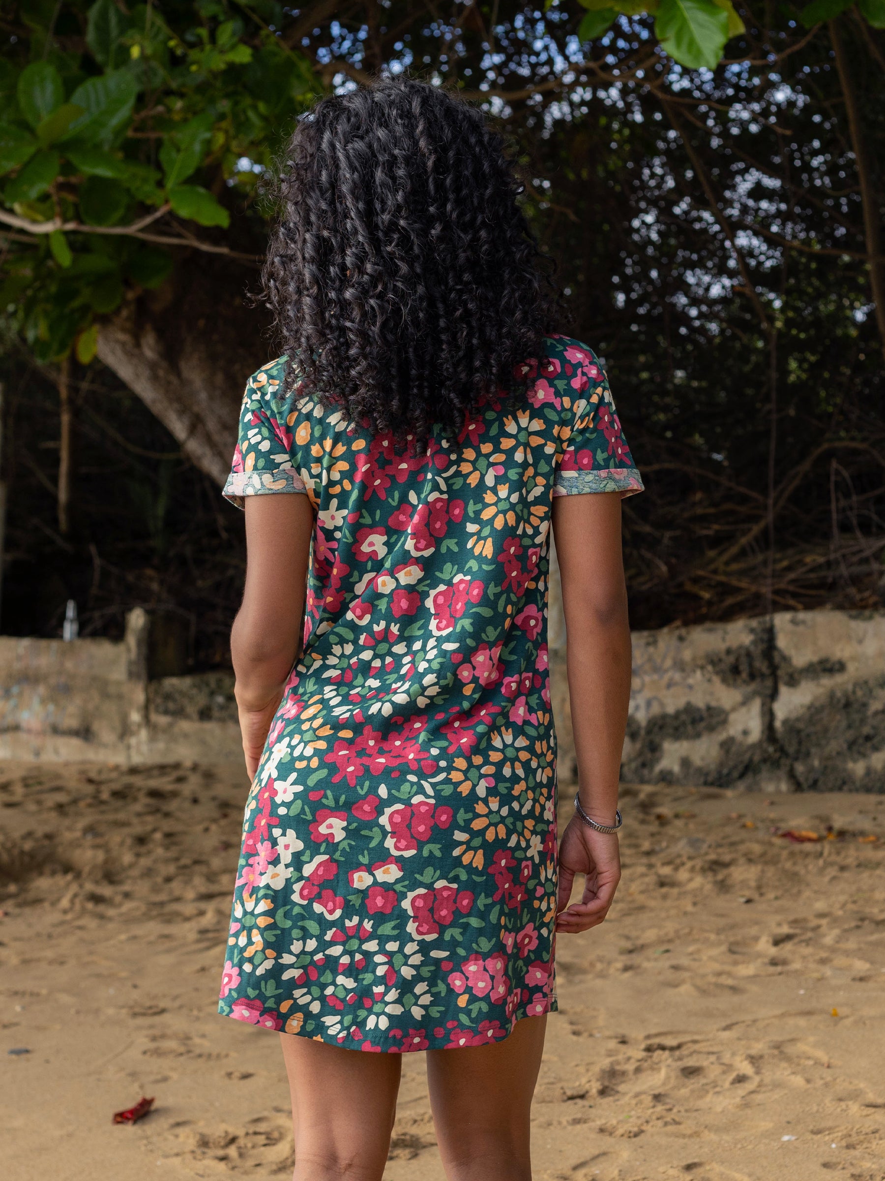 Woman from behind wearing a green Finley Wildflowers organic cotton t-shirt dress with cuffed sleeves and scoop hem.