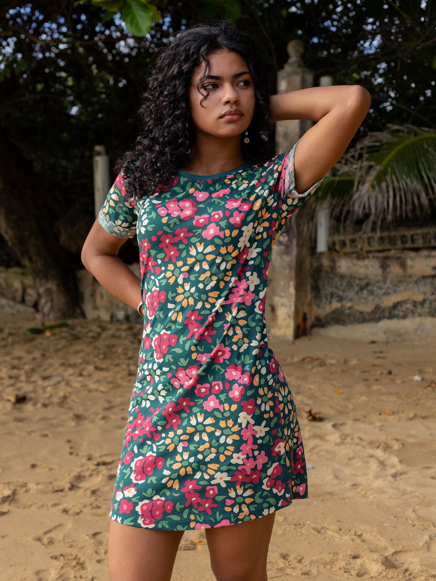 Woman in a green organic cotton Finley t-shirt dress with pink, red, and yellow wildflowers, cuffed sleeves, and a scoop hem.